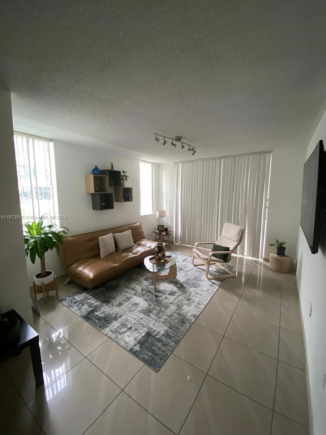 tiled living room featuring a textured ceiling and track lighting