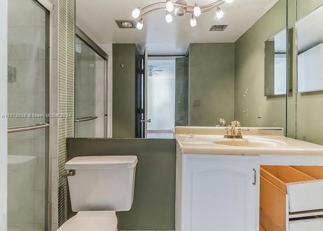 bathroom featuring a shower with shower door, vanity, and toilet