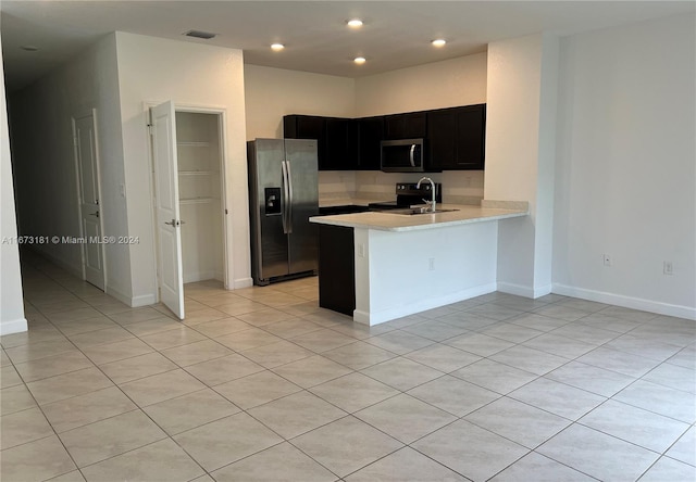 kitchen featuring light tile patterned floors, sink, appliances with stainless steel finishes, and kitchen peninsula