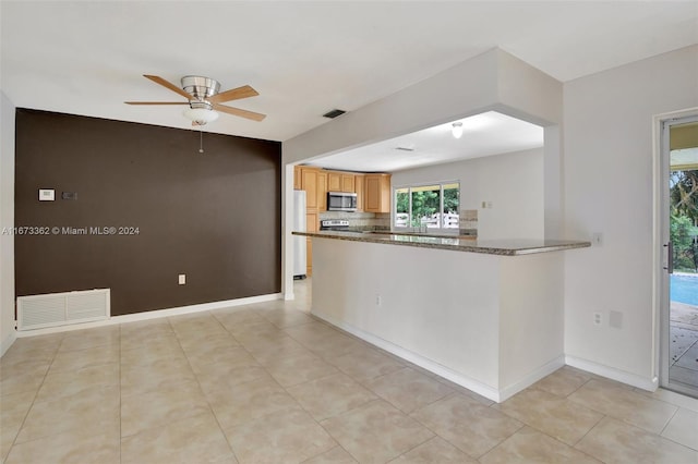 kitchen with ceiling fan, kitchen peninsula, tasteful backsplash, stainless steel appliances, and dark stone countertops