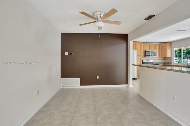 kitchen featuring light stone counters, light tile patterned flooring, backsplash, appliances with stainless steel finishes, and ceiling fan