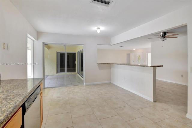 kitchen with dark stone counters, kitchen peninsula, dishwasher, and light tile patterned floors