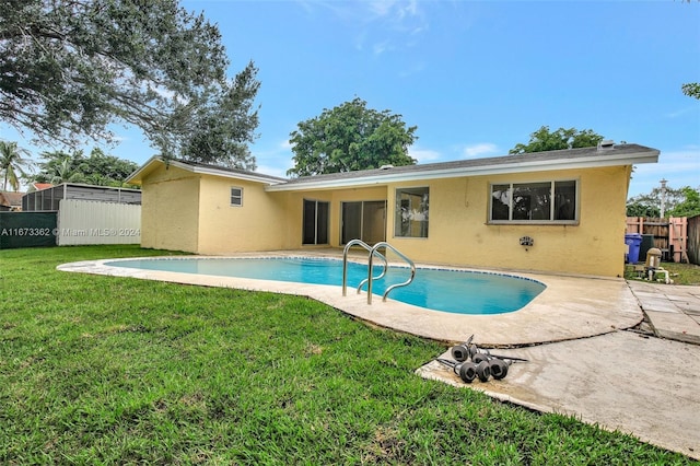 rear view of house with a lawn, a fenced in pool, and a patio area