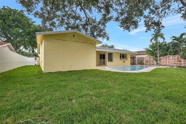 back of house featuring a fenced in pool and a lawn