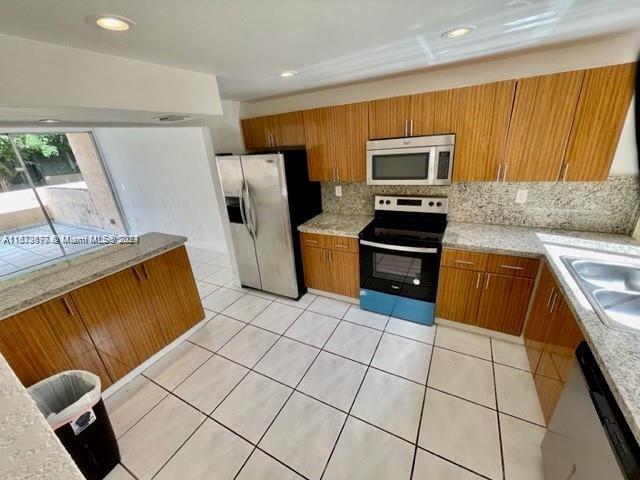 9173 Fontainebleau Blvd Unit 3, Miami, FL 33172 - kitchen featuring stainless steel appliances, brown cabinetry, tasteful backsplash, light countertops, and recessed lighting