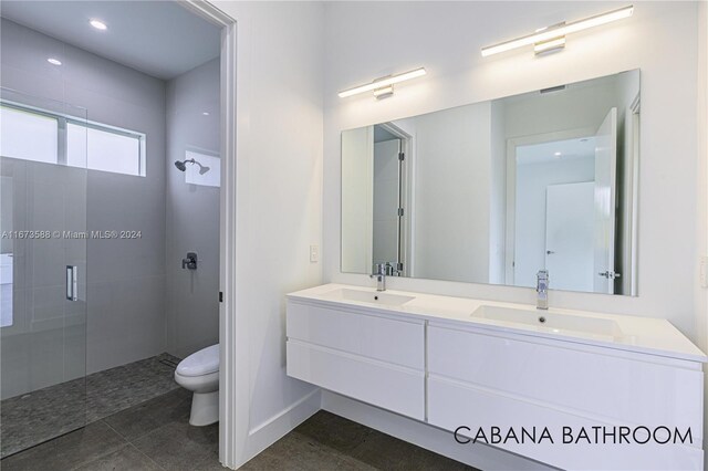 bathroom featuring tile patterned flooring, vanity, a shower with door, and toilet