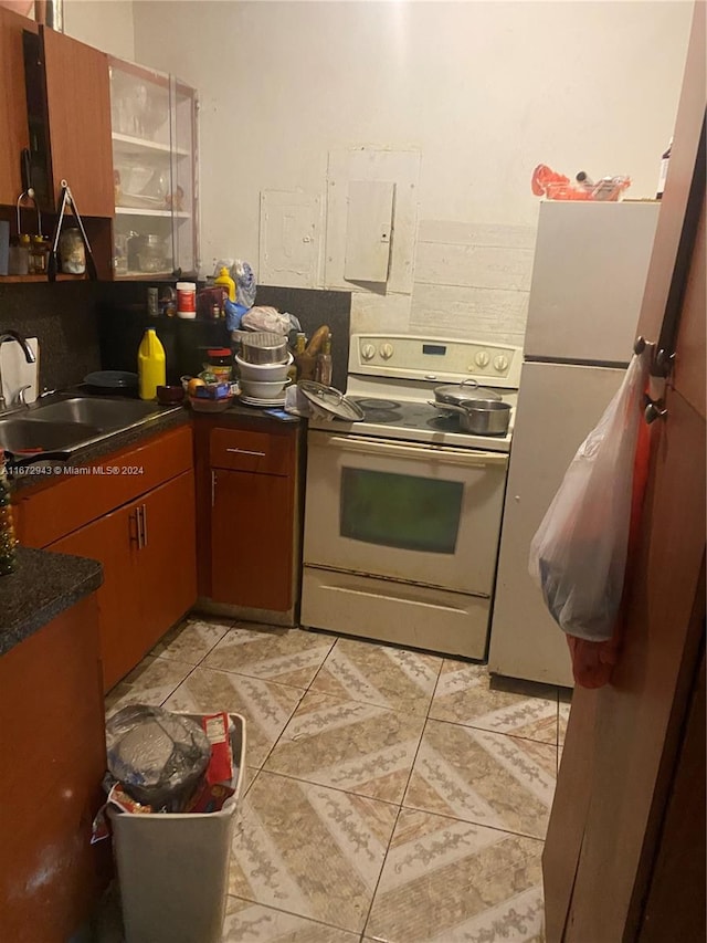 kitchen with white electric range oven, light tile patterned floors, and sink