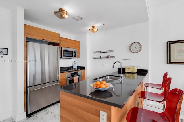 kitchen featuring a breakfast bar, sink, kitchen peninsula, and stainless steel appliances