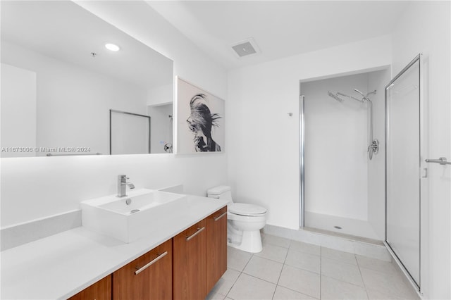 bathroom with tile patterned flooring, vanity, toilet, and walk in shower