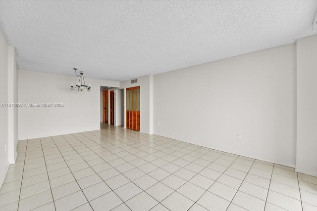 unfurnished room featuring light tile patterned floors, a textured ceiling, and an inviting chandelier