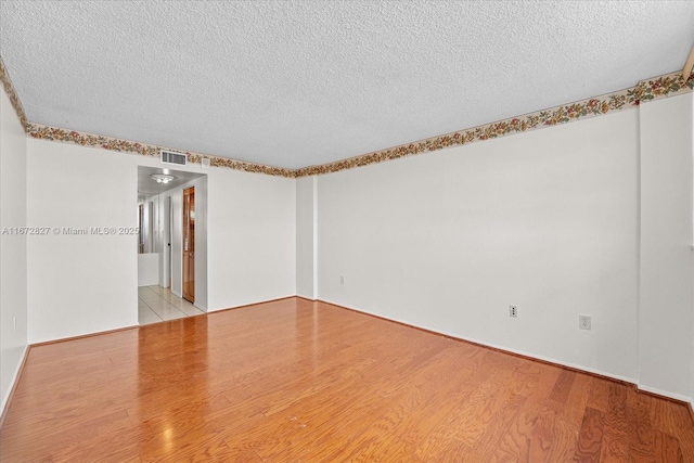 spare room with light wood-type flooring and a textured ceiling