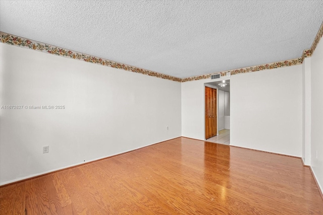 empty room with light hardwood / wood-style floors and a textured ceiling