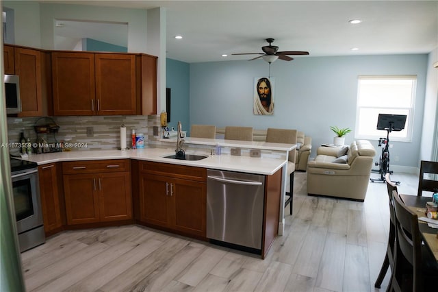 kitchen featuring stainless steel appliances, kitchen peninsula, sink, and light wood-type flooring