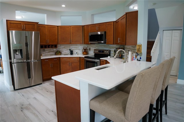 kitchen with kitchen peninsula, a kitchen bar, sink, and stainless steel appliances