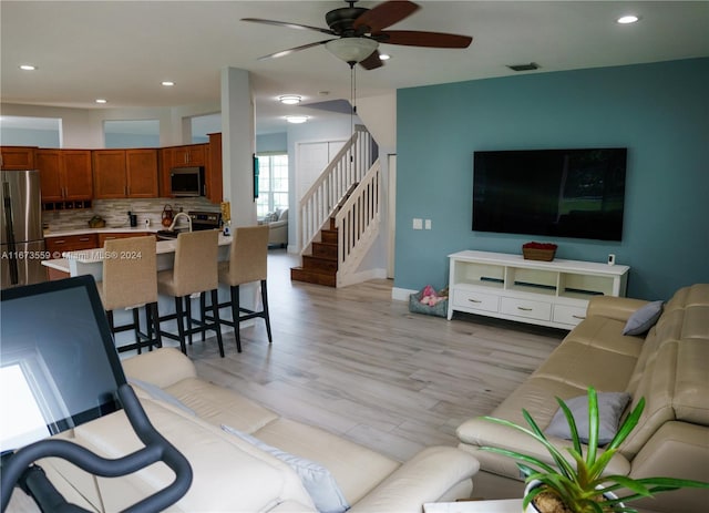 living room featuring ceiling fan and light hardwood / wood-style flooring