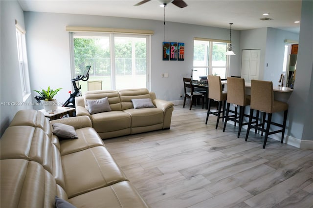 living room with a wealth of natural light, light wood-type flooring, and ceiling fan