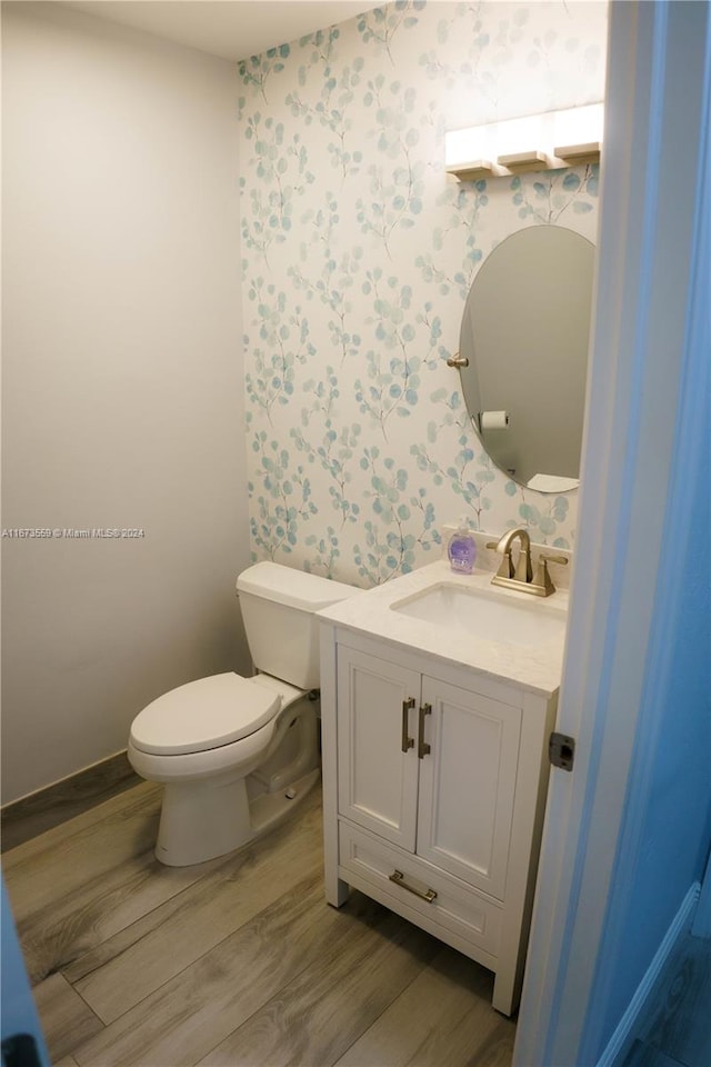 bathroom with hardwood / wood-style flooring, vanity, and toilet