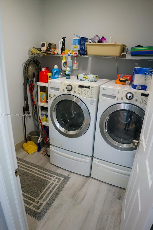 laundry area featuring washing machine and clothes dryer and light hardwood / wood-style floors