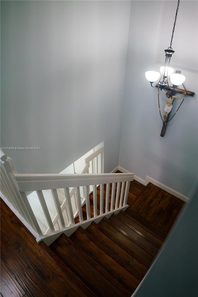 stairway with an inviting chandelier and hardwood / wood-style floors