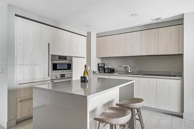 kitchen featuring light brown cabinets, a kitchen island, a kitchen bar, and sink