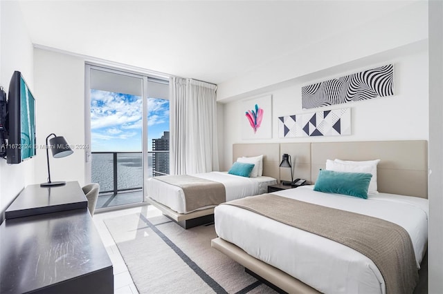 bedroom featuring a water view, light tile patterned flooring, and access to exterior