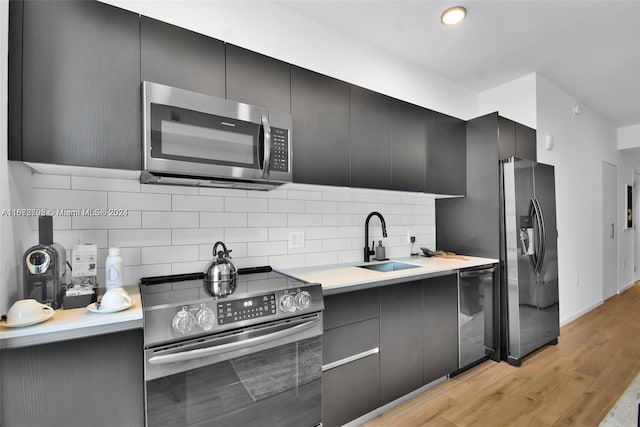 kitchen featuring backsplash, light hardwood / wood-style floors, sink, and appliances with stainless steel finishes