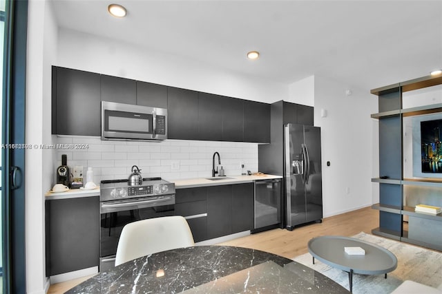 kitchen featuring backsplash, stainless steel appliances, light hardwood / wood-style flooring, and sink