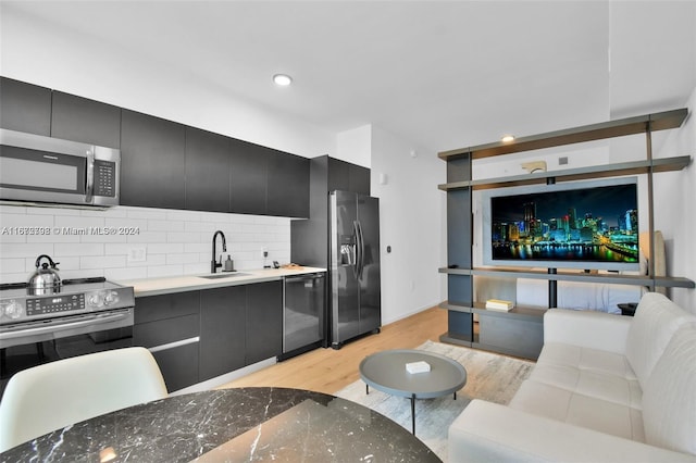 kitchen featuring decorative backsplash, appliances with stainless steel finishes, light wood-type flooring, and sink