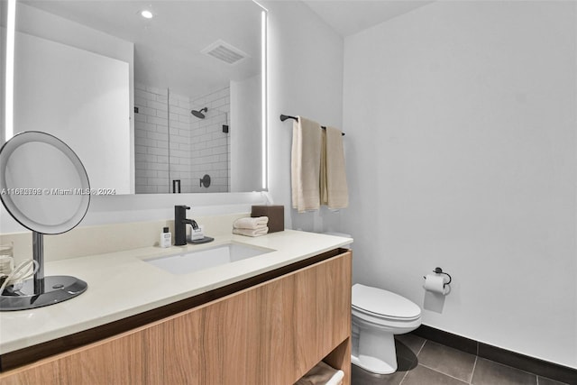 bathroom featuring tile patterned floors, vanity, a shower with shower door, and toilet