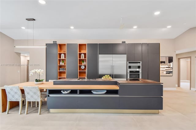 kitchen featuring pendant lighting, lofted ceiling, a breakfast bar, stainless steel appliances, and a large island with sink