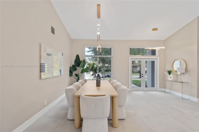 carpeted dining room featuring french doors, lofted ceiling, and plenty of natural light