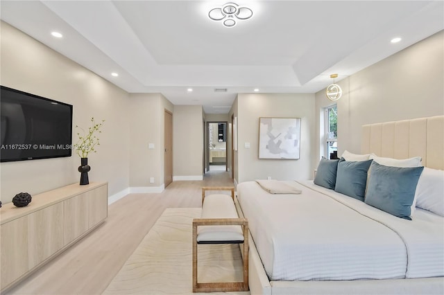 bedroom with a tray ceiling and light hardwood / wood-style floors