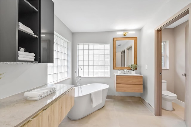 bathroom with tile patterned flooring, vanity, a washtub, and toilet