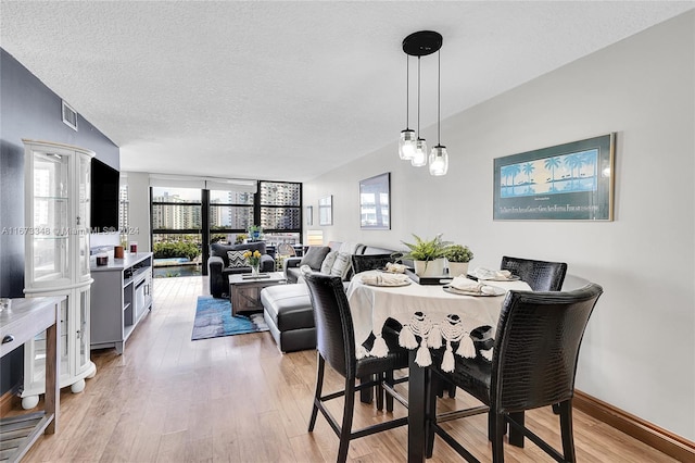 dining space with light hardwood / wood-style floors and a textured ceiling