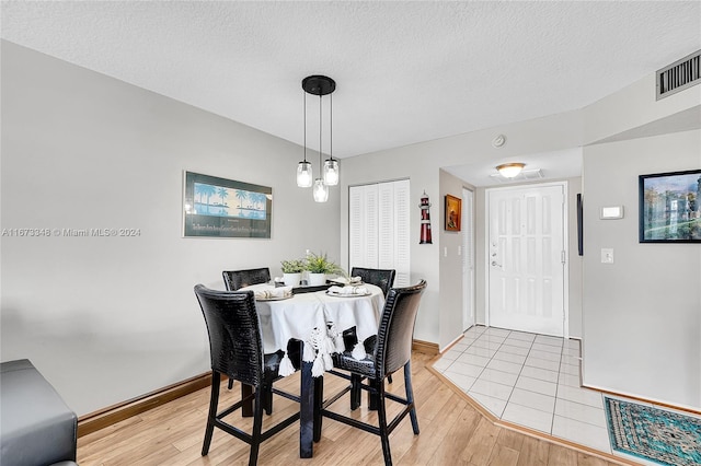 dining room with light hardwood / wood-style flooring and a textured ceiling