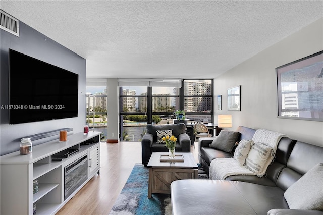 living room with light hardwood / wood-style floors, a textured ceiling, and a wealth of natural light