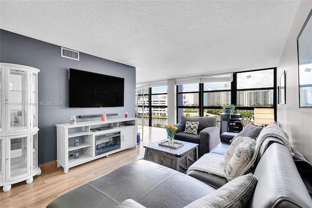 living room featuring a textured ceiling, light wood-type flooring, and a wall of windows