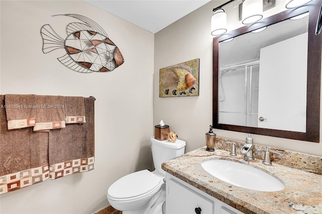 bathroom featuring toilet, an enclosed shower, and vanity