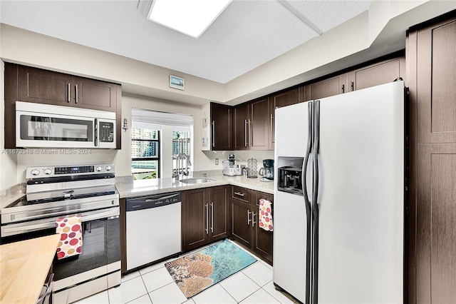 kitchen featuring sink, dark brown cabinetry, stainless steel appliances, and light tile patterned floors