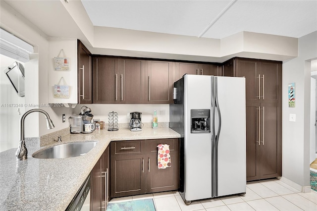 kitchen with light tile patterned floors, white fridge with ice dispenser, dark brown cabinets, and sink