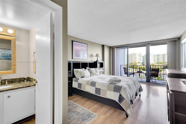 bedroom with hardwood / wood-style flooring, access to outside, a textured ceiling, and expansive windows