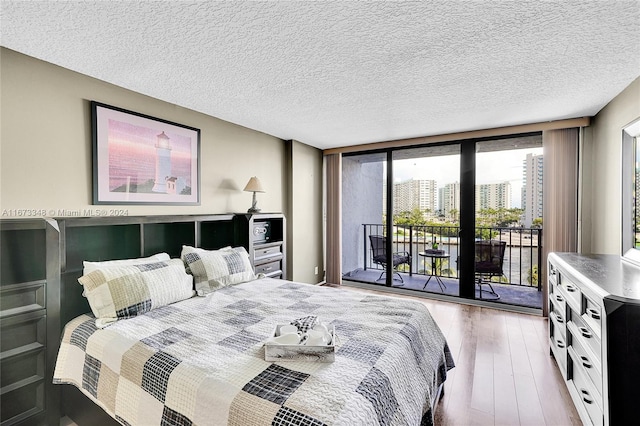 bedroom featuring a textured ceiling, access to outside, wood-type flooring, and expansive windows