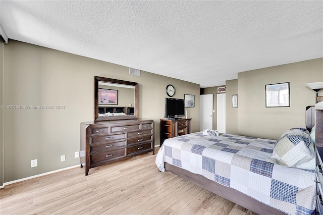 bedroom with a textured ceiling and light wood-type flooring