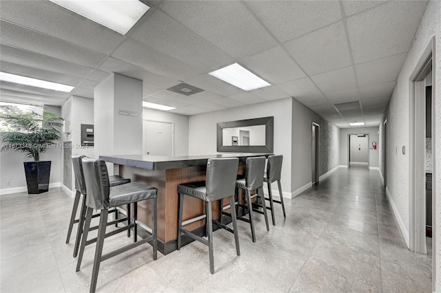 kitchen with a breakfast bar, kitchen peninsula, and a paneled ceiling