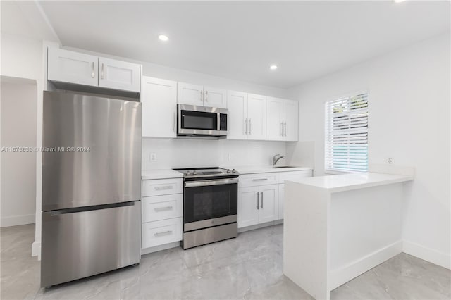 kitchen with white cabinetry, appliances with stainless steel finishes, sink, and kitchen peninsula