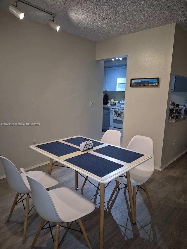 dining room featuring track lighting, wood-type flooring, and a textured ceiling