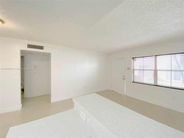 unfurnished room with a textured ceiling