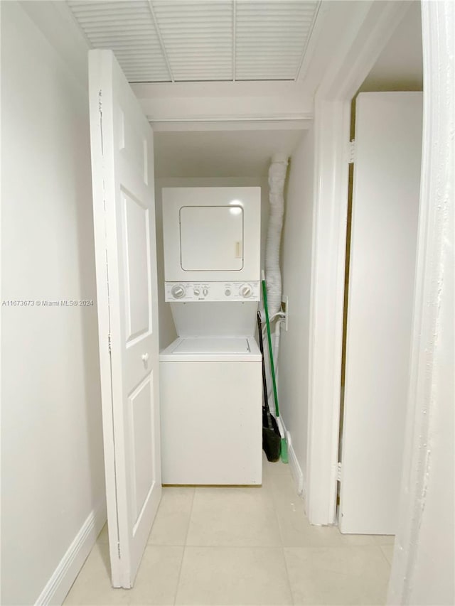 laundry area with light tile patterned floors and stacked washer and dryer