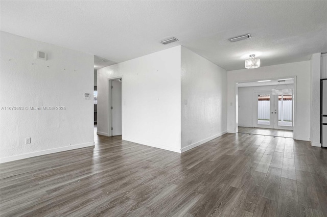 spare room featuring visible vents, dark wood finished floors, a textured ceiling, and french doors