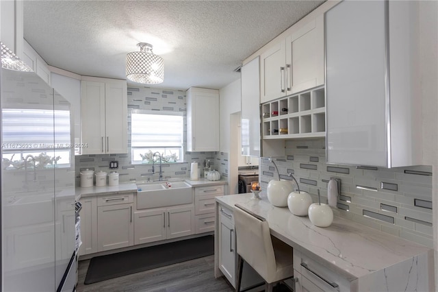 kitchen featuring sink, backsplash, dark hardwood / wood-style flooring, and white cabinetry